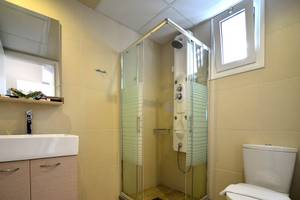 Badezimmer im Kalyves Beach Hotel mit Glasdusche, Waschbecken und Toilette.