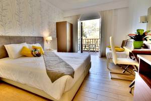 Ein modernes Schlafzimmer im Kalyves Beach Hotel mit einem Doppelbett, Balkonzugang und Wohnzimmermöbeln.