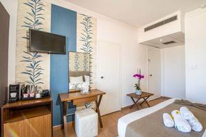 Innenansicht eines Zimmers im Kalyves Beach Hotel mit Bett, Fernseher und Dekor.
