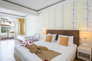 Schlafzimmer im Kalyves Beach Hotel mit zwei Betten, Dekor und Aussicht durch eine Terrassentür.