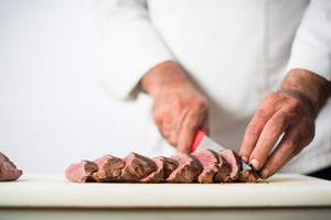 Koch beim Schneiden eines Steaks im Hersonissos Maris Hotel.