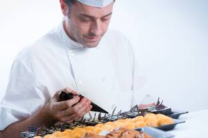 Ein Koch im Hersonissos Maris Hotel dekoriert ein Gebäckstück.