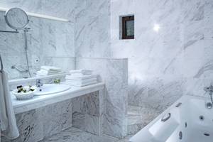 Badezimmer im Hersonissos Maris Hotel mit weißen Marmorfliesen und einer Badewanne.