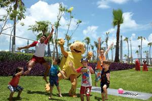 Kinder und ein Mitarbeiter im Riu Palace Peninsula spielen auf der Wiese.