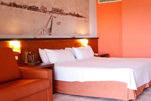 Hotelzimmer im Occidental Arenas Blancas mit Bett, Kissen, Stuhl und Wandmalerei.