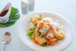 Ein Teller mit einem Salatgericht im Beyond Resort Khao Lak, serviert mit Soße und Besteck.