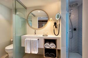 Badezimmer im Guayarmina Princess Hotel mit Rundspiegel, Waschbecken, Föhn und Dusche