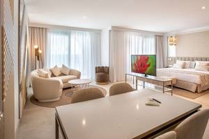 Schlafzimmer im Guayarmina Princess Hotel mit einem großen Bett, Couch, Tisch und Fernseher.