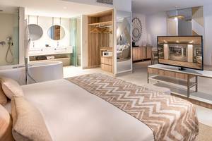 Innenansicht der Suite im Guayarmina Princess Hotel mit Bett, Fernseher und Badezimmer.