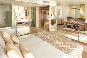 Innenansicht eines Zimmers im Guayarmina Princess Hotel mit Bett, Badewanne und Fernseher.
