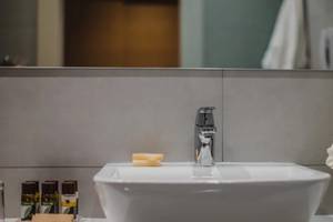 Badezimmer im Alion Beach Hotel mit Waschbecken, Seife und Blumen.