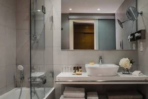 Modernes Badezimmer im Alion Beach Hotel mit Badewanne, Waschbecken und Glasdusche