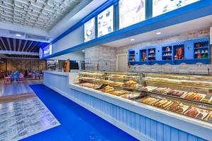 Innenansicht des Cafes im Crystal Admiral Resort Suites & Spa mit Kuchen und Gebäck auf dem Tresen
