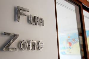 Das Schild mit dem Wort 'Fun Zone' ist an einer Wand befestigt.