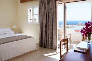 Zimmer im Mitsis Family Village Beach Hotel mit Balkon und Meerblick, Bett, Schreibtisch und Fenster.