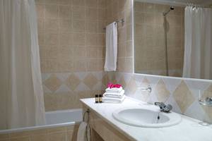 Badezimmer im Mitsis Family Village Beach Hotel mit Badewanne, Waschbecken und Handtüchern