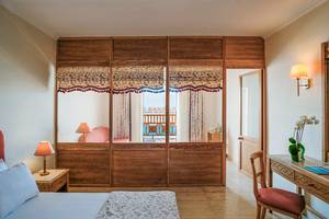 Innenansicht eines Zimmers im Mitsis Family Village Beach Hotel mit Blick auf eine Terrasse und das Meer.