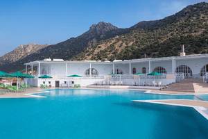 Außenpool des Mitsis Family Village Beach Hotels mit grünen Sonnenschirmen und Liegestühlen.