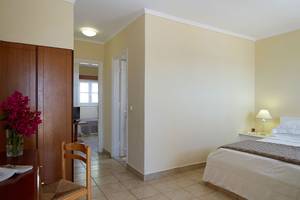 Schlafzimmer im Mitsis Family Village Beach Hotel mit Bett, Nachttisch und Dekor.