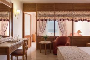 Schlafzimmer im Mitsis Family Village Beach Hotel mit Fenstern, Vorhängen und einem Ausblick auf das Meer.