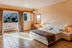 Innenansicht eines Zimmers im Mitsis Family Village Beach Hotel mit Bett, Schreibtisch und Balkon