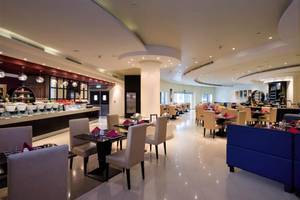 Innenansicht des Restaurants im Al Hamra Residence Hotel mit gepolsterten Stühlen und Tischen.