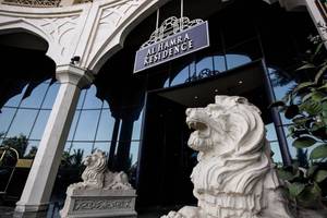 Eingang zur Al Hamra Residence mit zwei Löwenstatuen vor einer Glasfassade.