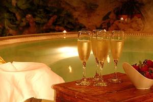 Eine Frau genießt ein Getränk in einem beleuchteten Whirlpool mit Champagner und Erdbeeren.