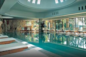Coral Beach Hotel & Resorts Pool mit Loungeliegen und großer Fensterfront.