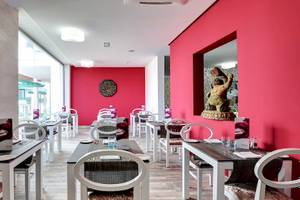 Restaurantbereich im Barceló Teguise Beach Adults Only Hotel mit roten Wänden und weißen Tischen.
