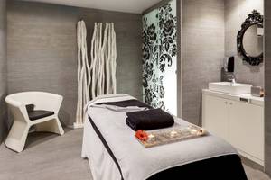 Spa-Behandlungsraum im Barceló Teguise Beach Adults Only Hotel mit Liege, Stuhl und Waschbecken.