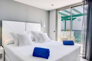 Zimmer im Barceló Teguise Beach Adults Only Hotel mit einem Bett, weißen Kissen und blauen Handtüchern.