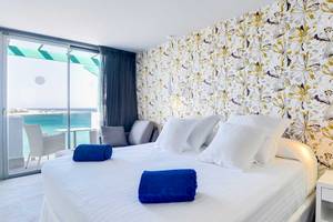 Hotelzimmer im Barceló Teguise Beach Adults Only mit Blick auf das Meer und blauen Handtüchern auf dem Bett.
