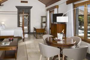Innenansicht der Suite im Melia Salinas Hotel mit großem Bett, Wohnzimmerbereich und Esstisch.