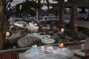 Terrasse im Melia Salinas Hotel mit Aussicht auf einen Wasserfall und Gartenlandschaft.