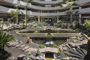Innenhof des Melia Salinas Hotels mit Brunnen, Pflanzen und gepflastertem Boden.