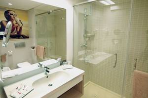 Badezimmer des Riu Gran Canaria Hotels mit Spiegel, Waschbecken, Dusche und Toilette.