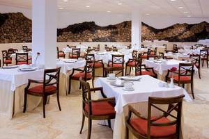 Speisesaal des Dreams Lanzarote Playa Dorada Resort & Spa mit weißen Tischen und roten Stühlen.