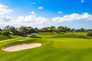 Golfplatz des Iberostar Grand Paraiso Hotels mit grünen Rasen und Bäumen.