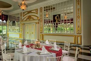 Speisesaal im Iberostar Grand Paraiso mit runden Tischen, eleganten Stühlen und Goldverzierungen.
