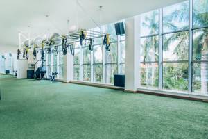 Fitnessstudio im Iberostar Grand Paraiso Hotel mit Blick auf Palmen und Außenbereich.