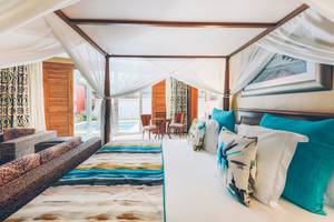 Suite im Iberostar Grand Paraiso mit einem Himmelbett und Baldachin, umgeben von Möbeln und einem Pool.