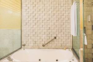 Badezimmer im Iberostar Grand Paraiso mit Badewanne, Handläufen und Fliesenwänden.