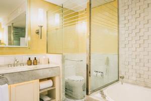 Badezimmer im Iberostar Grand Paraiso Hotel mit gelben Wänden, Marmorboden, Badewanne, Dusche und Toilette.