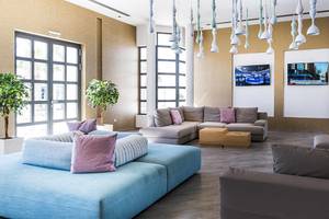 Lobby-Lounge des Club Plimmiri Hotels mit Sofas, Fernsehern und Pflanzen.