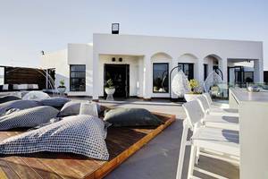 Die Dachterrasse des Club Plimmiri Hotels mit weißen Möbeln und Kissen, umgeben von Pflanzen.