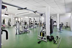 Fitnessstudio im Club Plimmiri Hotel mit verschiedenen Trainingsgeräten und grün glänzendem Boden.