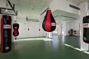 Fitnessraum im Club Plimmiri Hotel mit mehreren Boxsäcken und einer grünen Trainingsfläche.