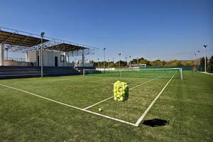 Tennisplatz des Club Plimmiri Hotels mit leeren Bänken und einem Ballkorb auf dem Feld