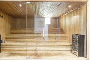 Innenansicht der Sauna im Club Plimmiri mit Holzbänken und Glaswänden.